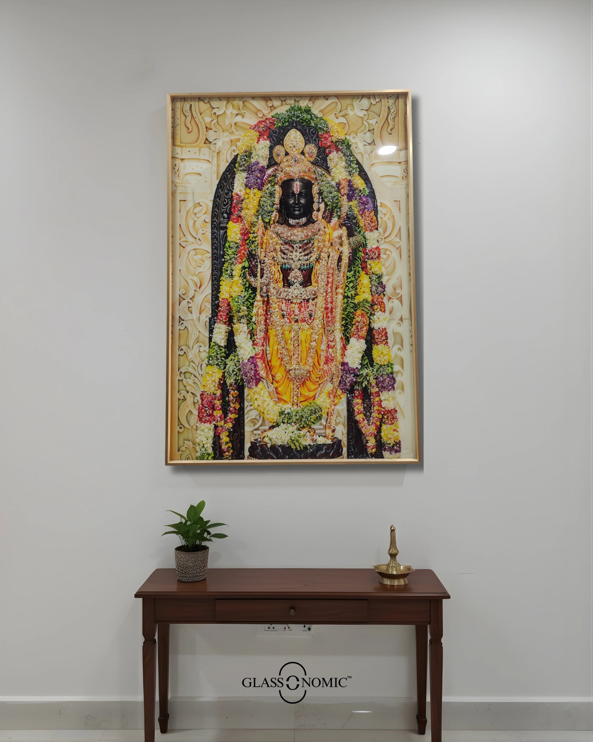 Decorative wall art of a deity with flowers on a white wall above a wooden console table.