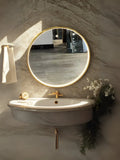 Bathroom setup with a round mirror, sink, and decorative elements on a textured wall.